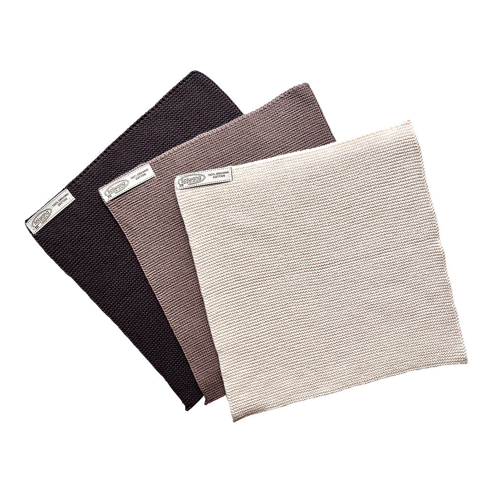 Solwang Design Vaatdoekjes set van 3 - Nature/Warm Grijs Combi drie gebreide doekjes gewaaierd over elkaar, van donkerbruin/antraciet achteraan via warm taupegrijs in het midden naar een lichte naturel tint vooraan, met het Solwang-label zichtbaar op elk doekje.