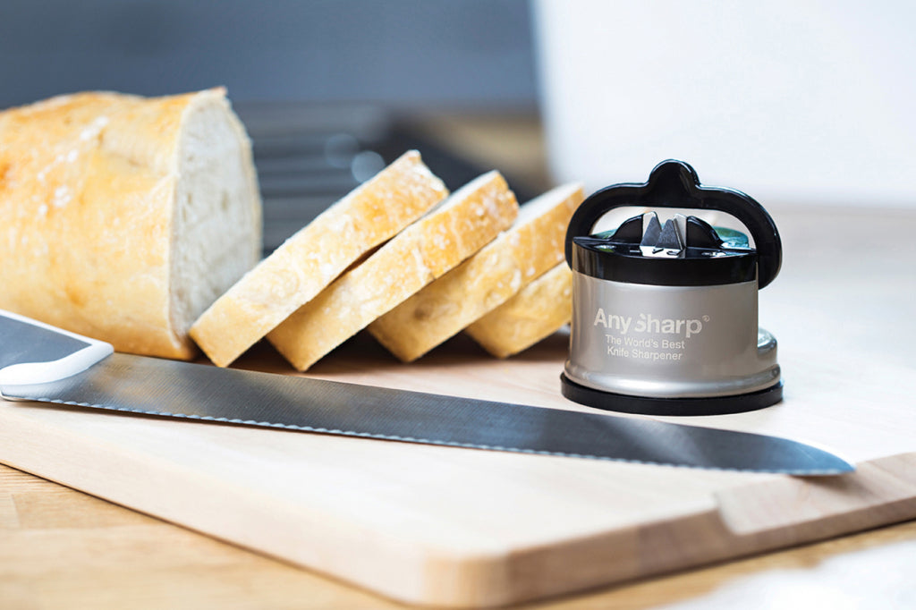 Anysharp messenslijper naast een broodmes en gesneden stokbrood op een houten plank