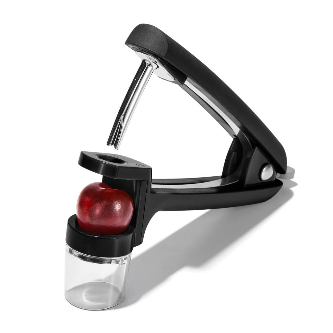 OXO Good Grips Kers- en Olijfontpitter, rode kers geplaatst in de ontpitkop met opvangbakje eronder