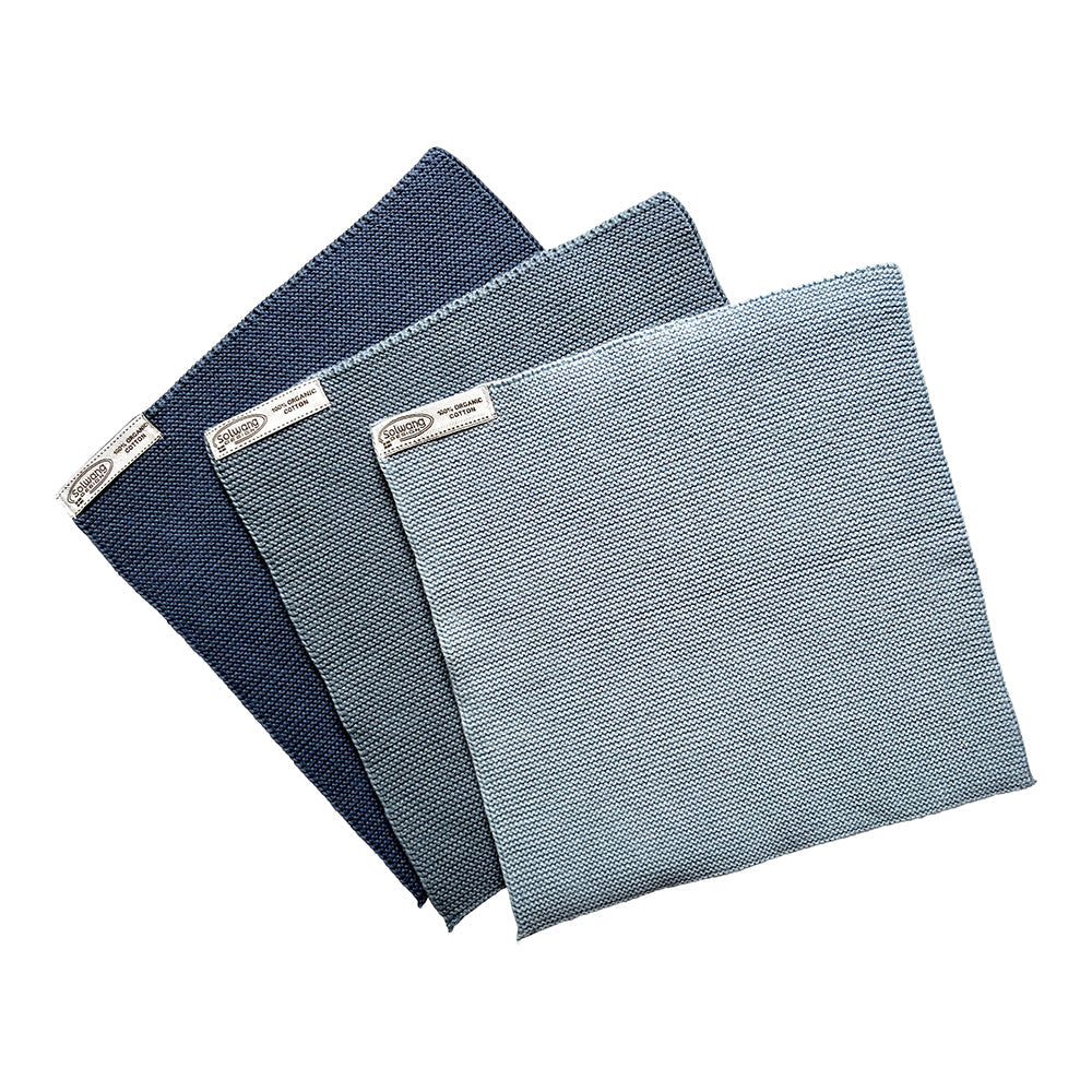 Solwang Design Vaatdoekjes set van 3 - Rustiek Blauw Combi drie gebreide doekjes gewaaierd over elkaar, allemaal in blauwtinten van donkerblauw achteraan via middenblauw naar een lichtblauwe tint vooraan, met het Solwang-label zichtbaar op elk doekje.
