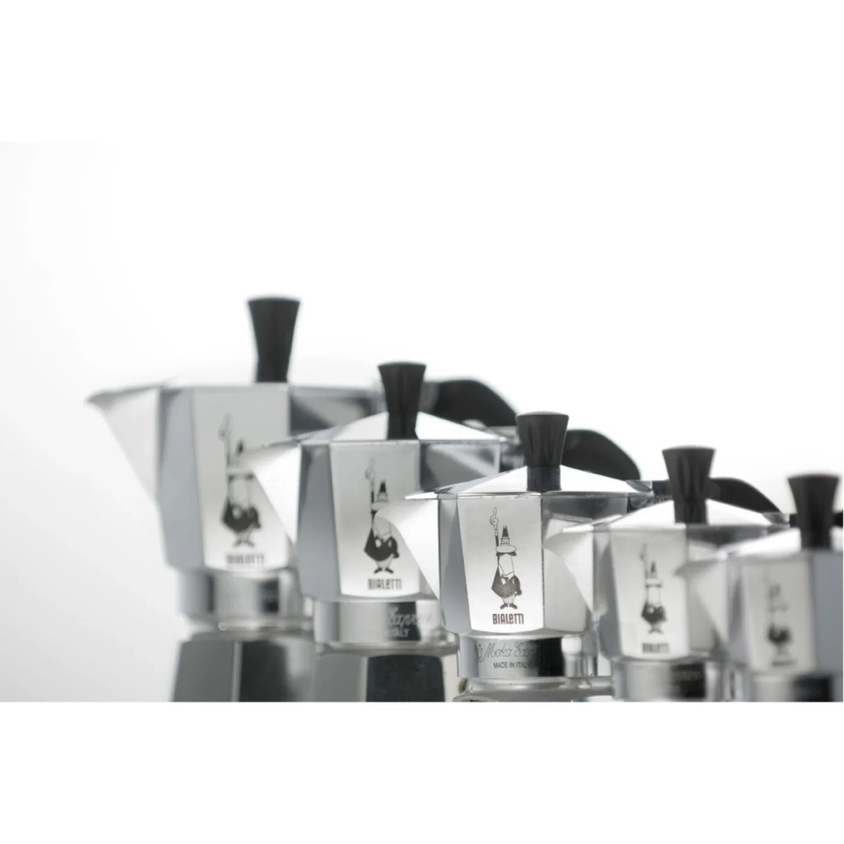 Rij zilveren Bialetti Moka Express percolators oplopend in maat op een witte achtergrond.