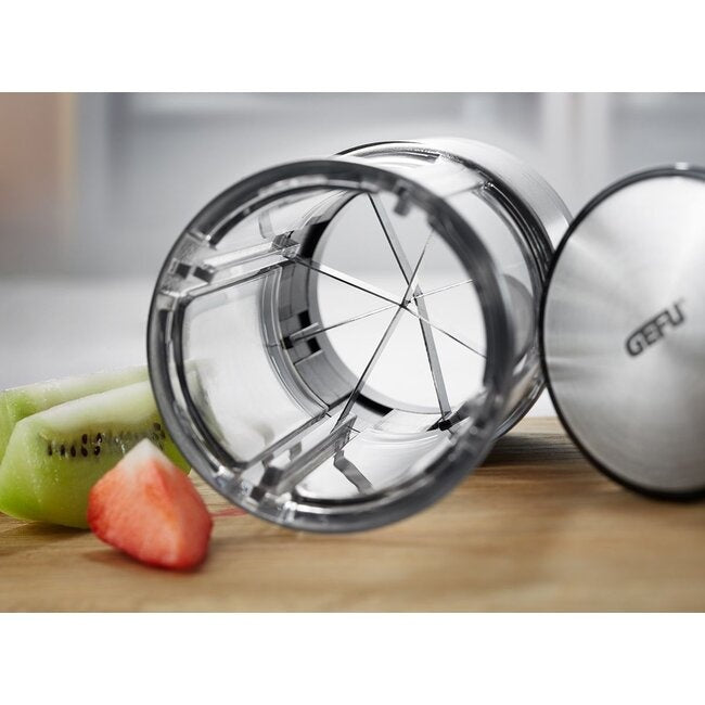 GEFU Groente- en Fruitsplitter Flexicut, close-up van de doorzichtige snijkop met het stervormige messenrooster, naast een gesneden aardbei en kiwi