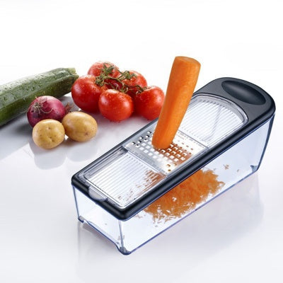 Westmark Technicus Quadro Raspenset, transparant, in gebruik met een wortel die wordt geraspt tussen tomaten, ui en aardappelen