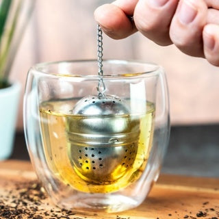 Westmark Teatime Ovaal Thee-ei, zilver, thee-ei hangt aan het kettinkje in een glas met thee