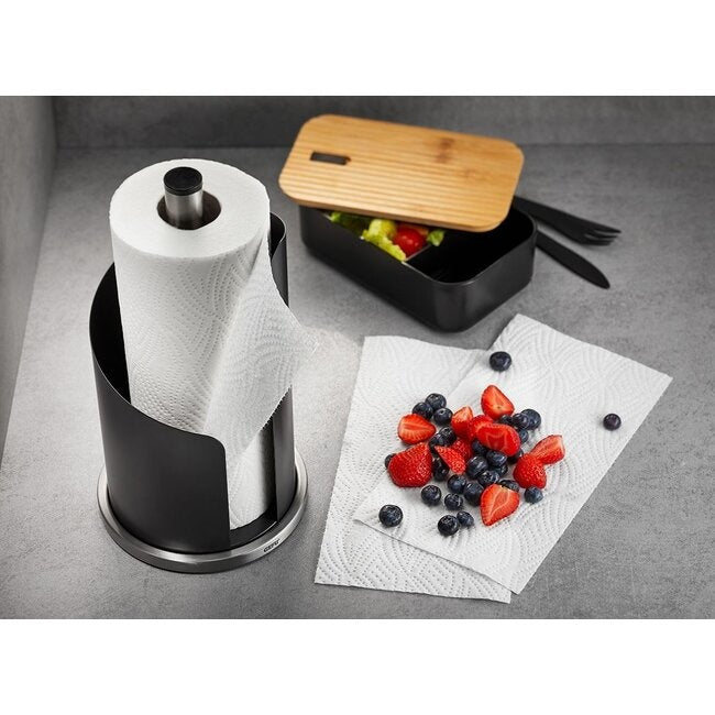 GEFU Keukenrolhouder Curve op een donker aanrecht naast een lunchbox met bamboe deksel gevuld met salade, met daarnaast een vel keukenpapier met aardbeien en blauwe bessen