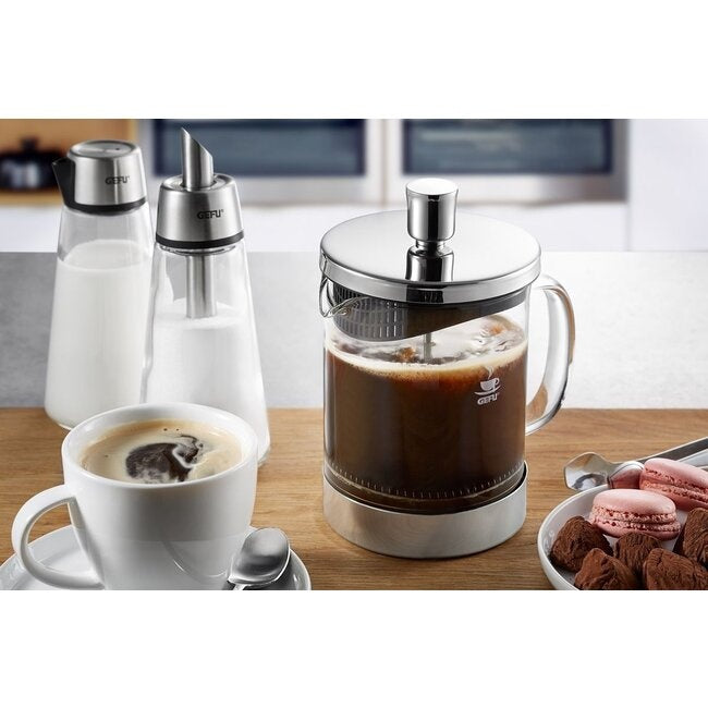 GEFU Cafetière Diego - 600 ml met zwarte koffie op een keukenblad naast bijpassende suiker- en melkkannetjes, een kopje koffie en een schaaltje macarons en bonbons