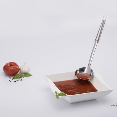 Westmark Glory Soeplepel, zilver, in gebruik bij een kom tomatensoep met verse tomaat en knoflook