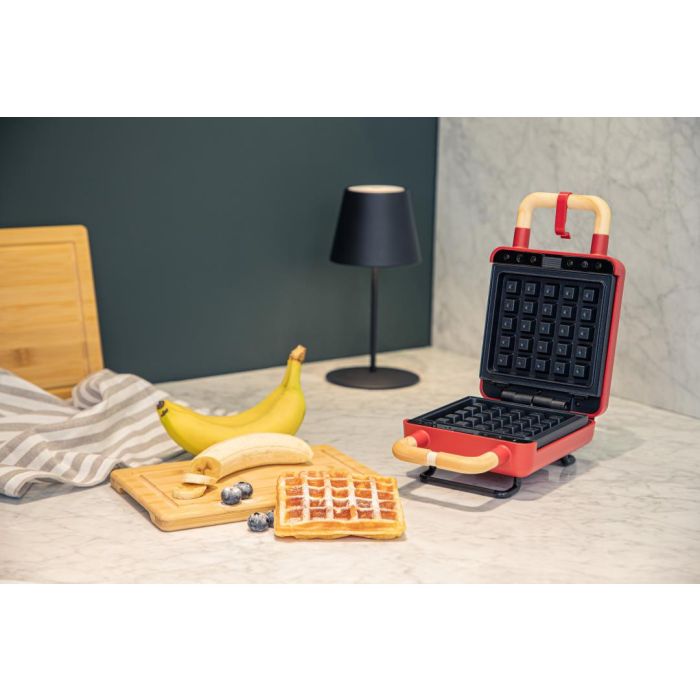 ADE rood wafel- en tosti-ijzer geopend op een marmeren aanrecht, met verse wafel en banaan