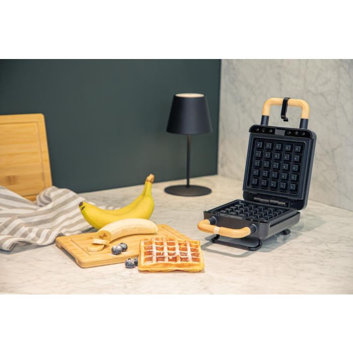 ADE zwart wafel- en tosti-ijzer geopend op een aanrecht, met verse wafel en banaan