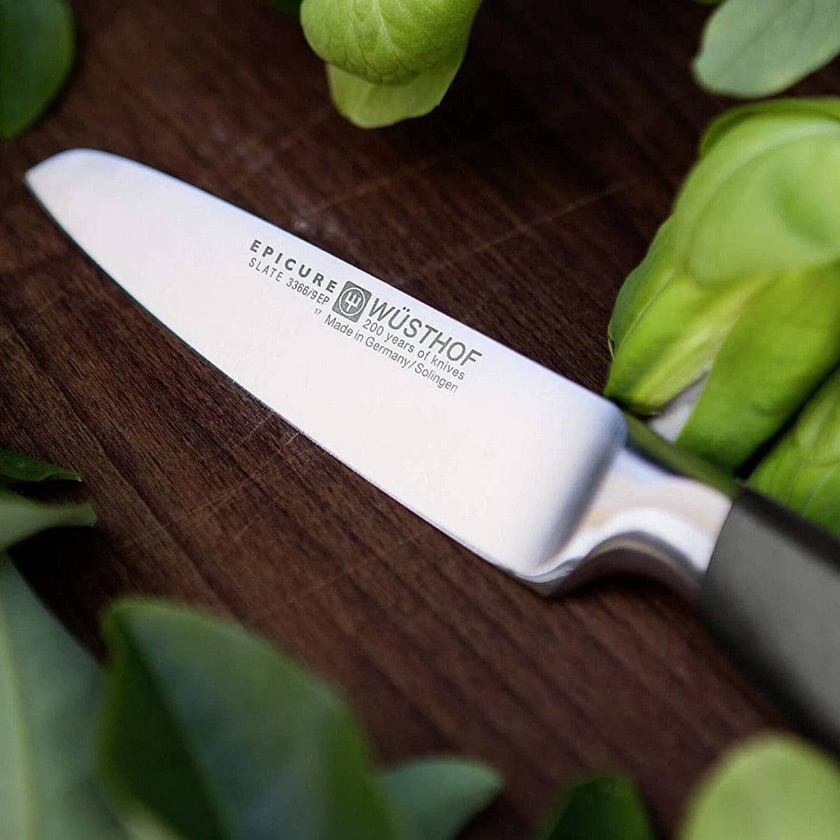 Wüsthof Epicure schilmes op een houten snijplank tussen verse groene bladgroente