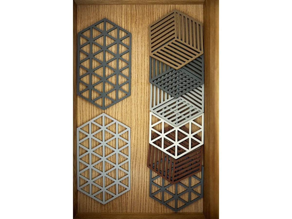 Open houten lade met twee grote grijze onderzetters met driehoekpatroon naast een stapel Hexagon onderzetters