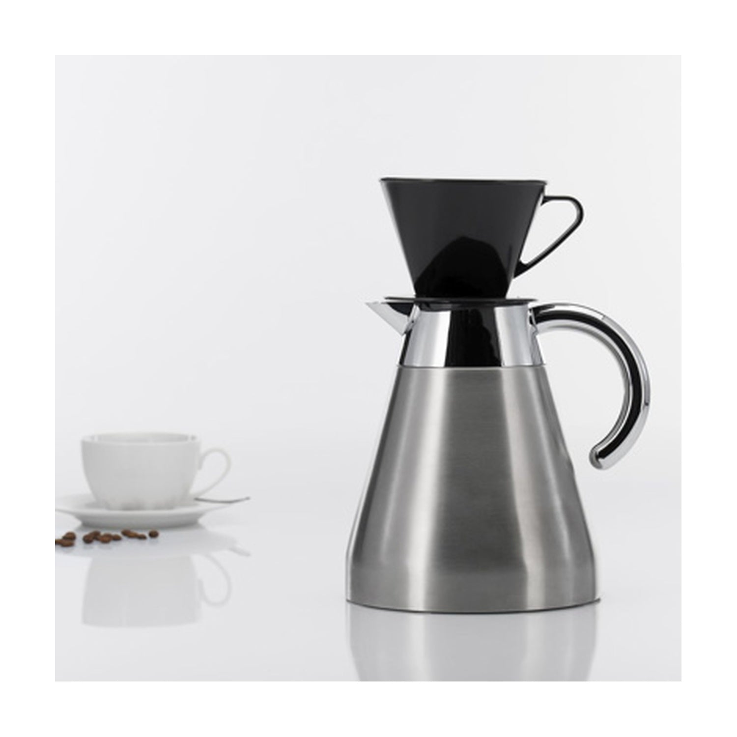 Westmark Koffiefilter, zwart, geplaatst op een RVS koffiekan naast een wit kopje en koffiebonen