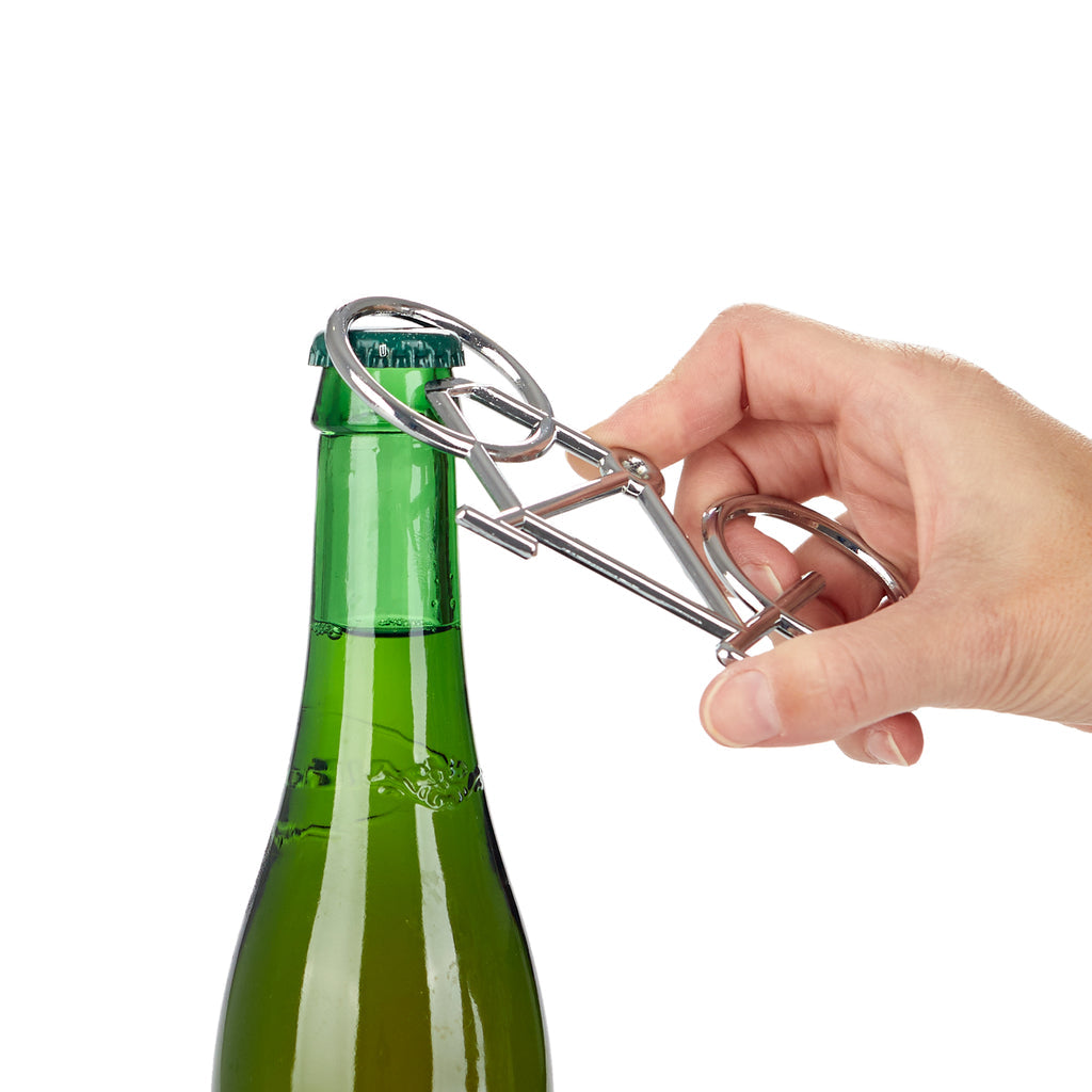 Hand opent een groen flesje met de fietsvormige opener, tegen een witte achtergrond
