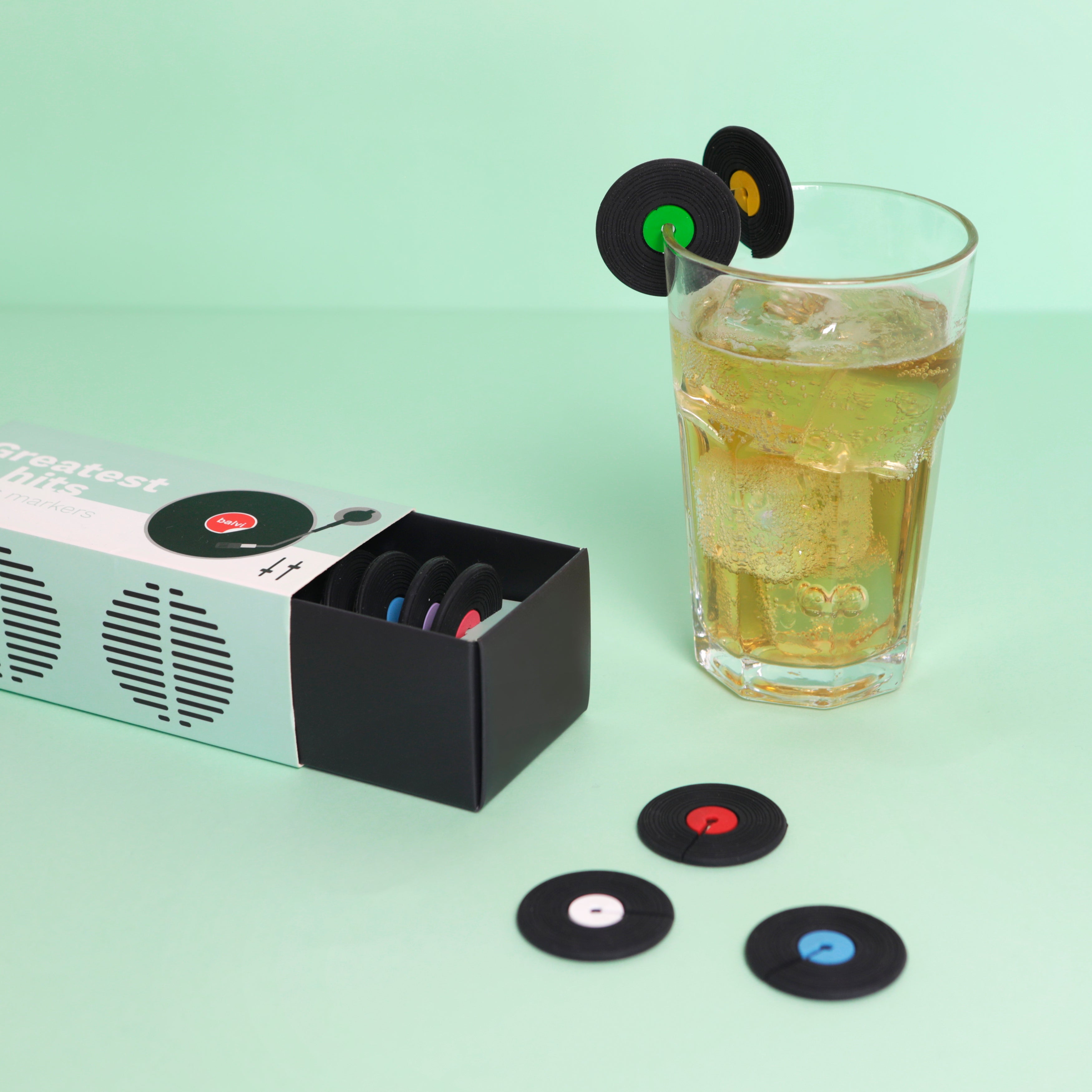 Balvi Glasmarkers Greatest Hits Siliconen - 8 stuks, bij een speaker naast een glas met marker, op mintgroene achtergrond
