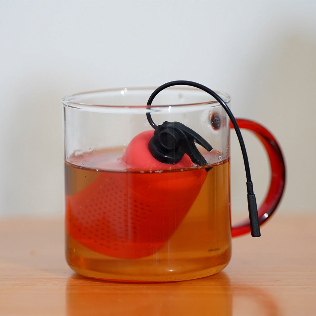 Balvi Thee-ei ExTEAnguisher, in een glazen theepot met ingeschonken thee