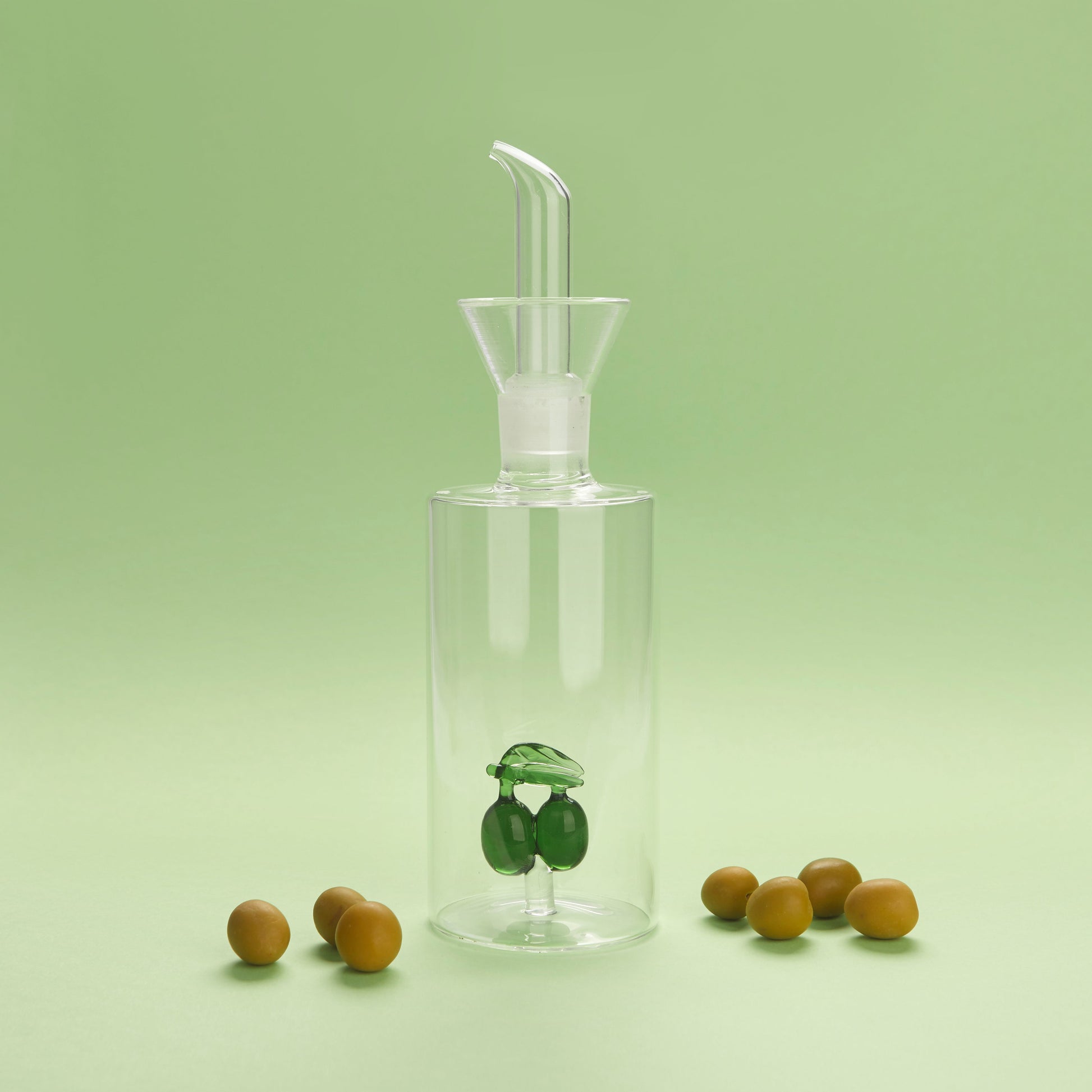 Balvi Olieschenker Olijf - 350 ml, op groene achtergrond met olijven