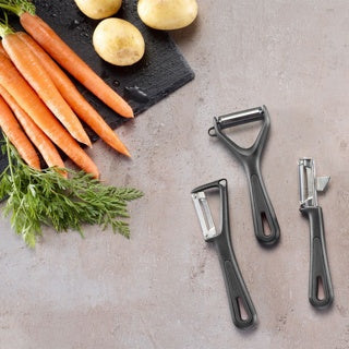 Westmark Gentle Swivel Peeler, zwart, naast andere Gentle-schilmesjes met wortelen en aardappels