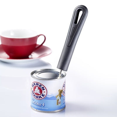 Westmark Gentle Blikprikker, zwart, in gebruik om een melkblikje te doorboren naast een kopje koffie