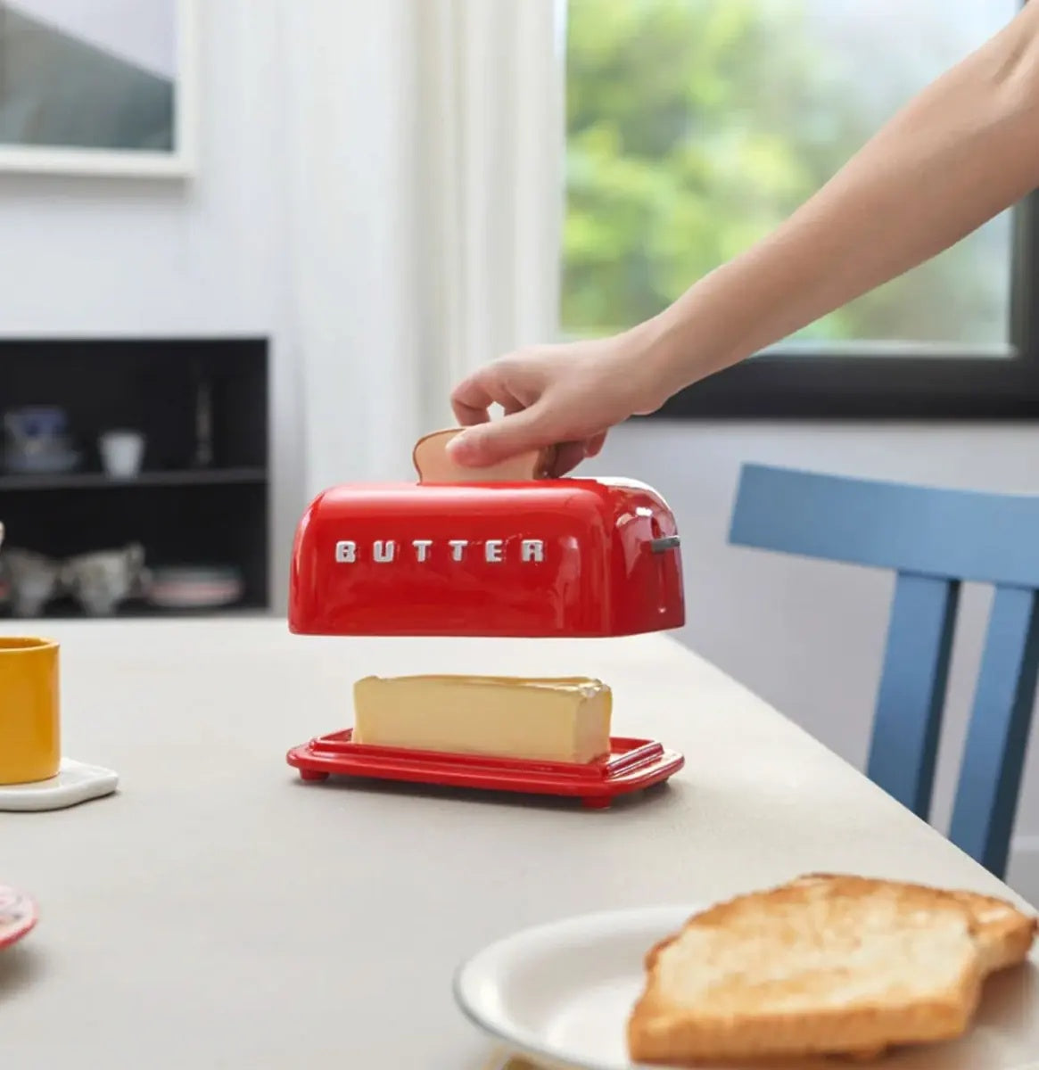 Balvi Botervloot Toasty Rood, op een keukentafel, hand pakt het deksel naast toast en jus