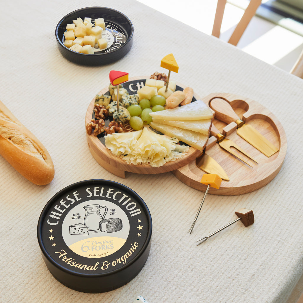Kaasplank op een gedekte tafel met kaas, druiven en noten, de vorkjes en het zwarte deksel op tafel