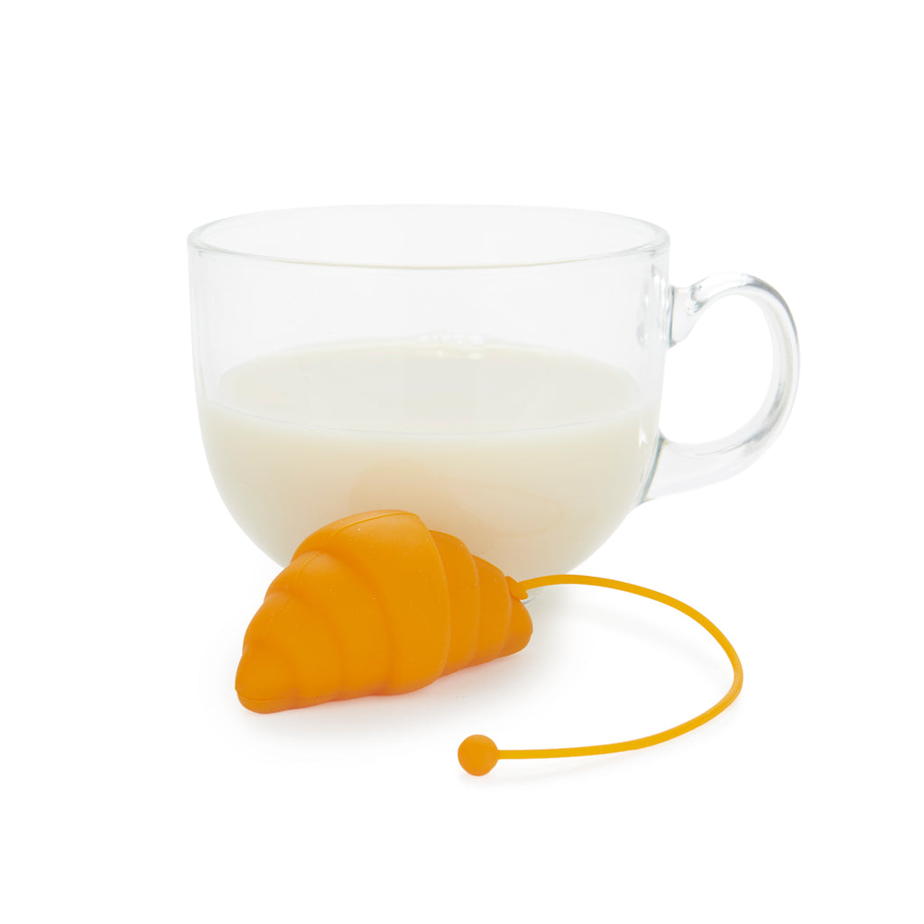 Oranjegeel croissant-thee-ei met koord naast een glazen kop op een witte achtergrond