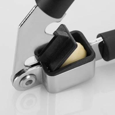 Westmark Gentle Knoflookpers, zwart, close-up van het pershoofd met een heel teentje knoflook erin, klaar om te persen
