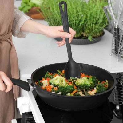 Westmark Gentle Groentelepel, zwart, in gebruik bij het roeren van groenten in een wokpan