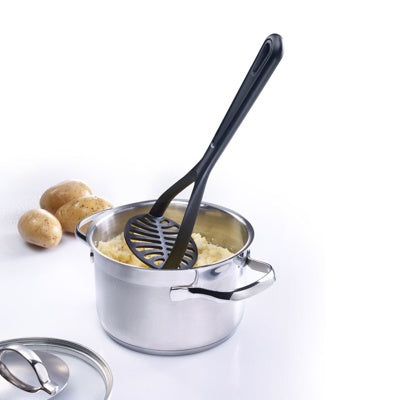 Westmark Gentle Aardappelstamper, zwart, in gebruik in een pan met gestampte aardappelen naast rauwe aardappelen