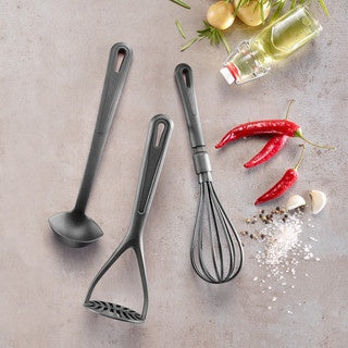 Westmark Gentle Aardappelstamper, zwart, samen met andere Gentle-keukengerei zoals een garde uitgestald op een stenen ondergrond