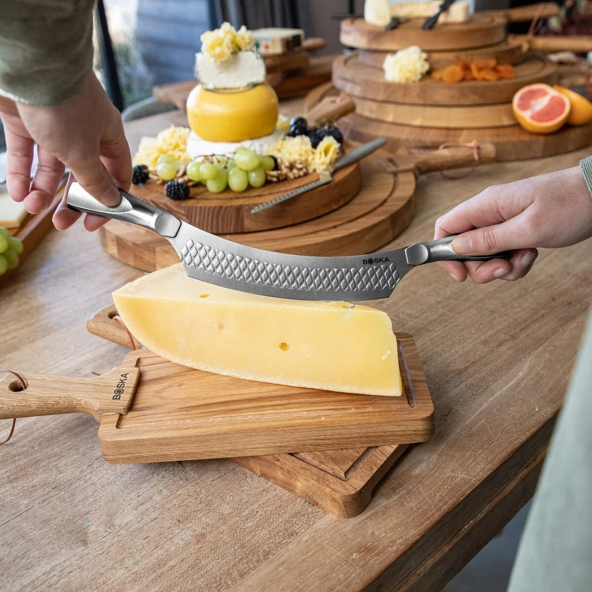 Boska Monaco+ Comté Mes Nr. 7 met twee handen gebruikt om een blok kaas te snijden