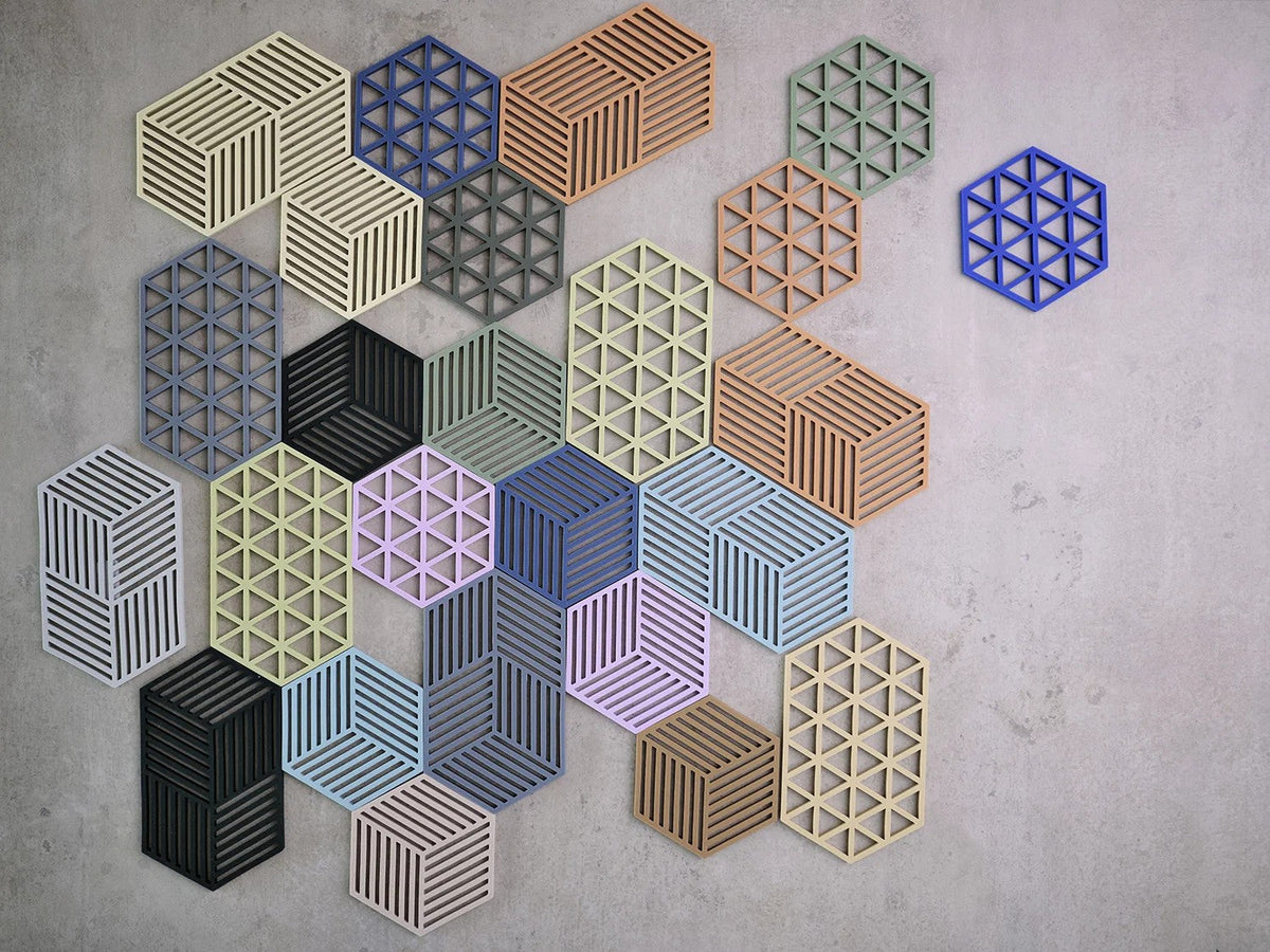 Onderzetters op een betonnen ondergrond, met rechtsboven een felblauwe Triangles apart van de rest