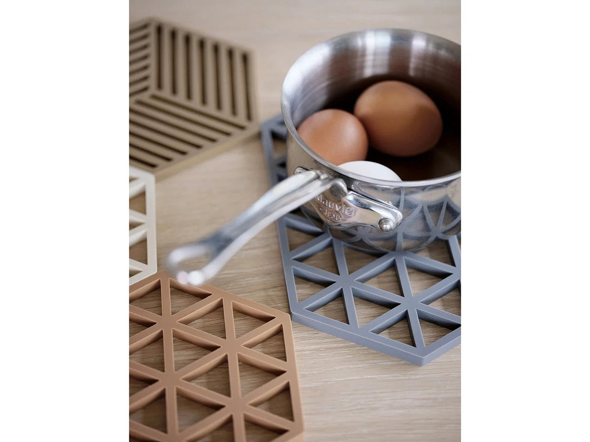 Steelpan met twee bruine eieren op een grijsblauwe onderzetter, linksonder een karamelbruine Triangles