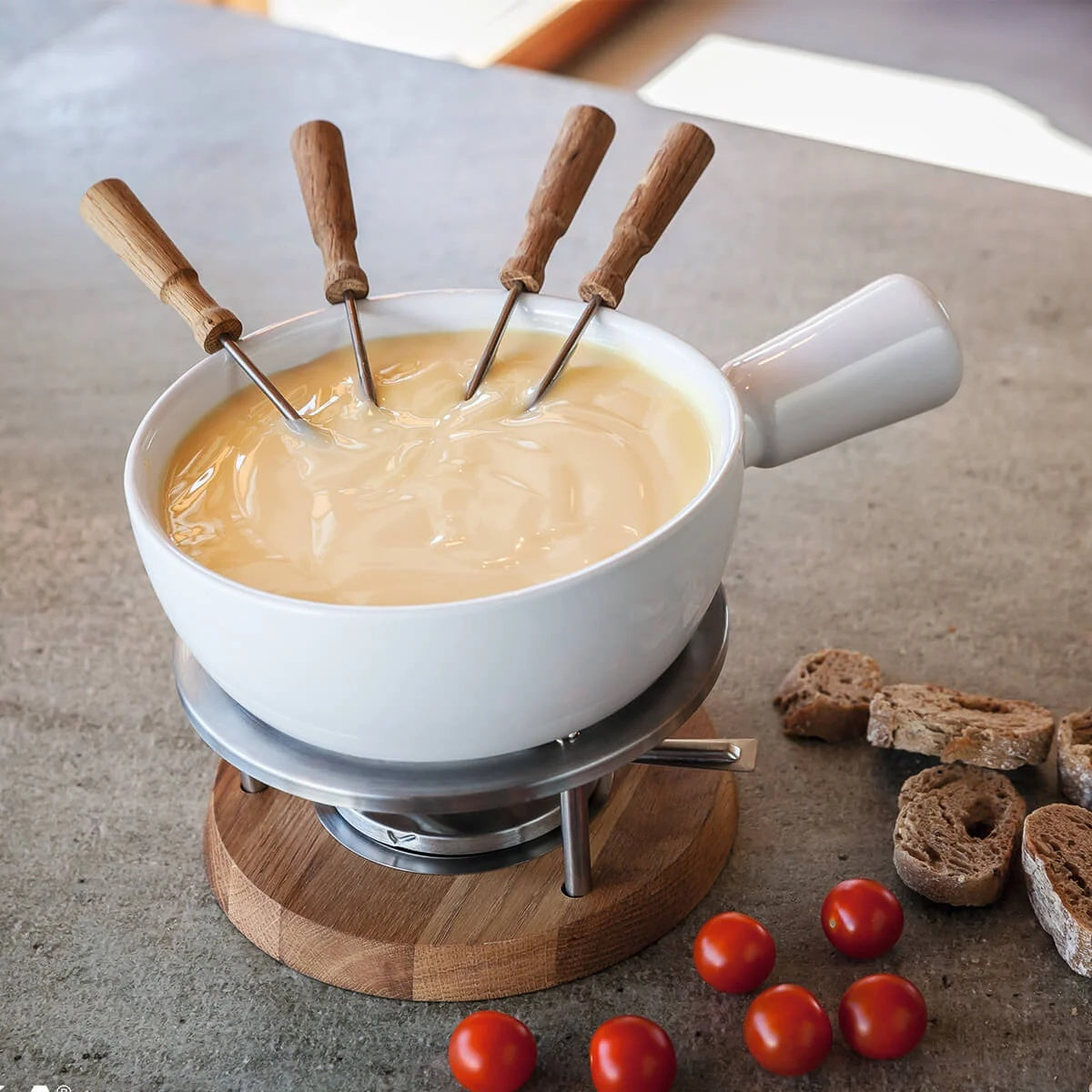 Boska Oslo Fonduevorken in een pan gesmolten kaas, met brood en tomaatjes ernaast
