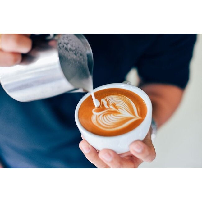GEFU Melkkan Barista - 350 ml, close-up van een hand die melk uit de kan in een kop giet voor latte art