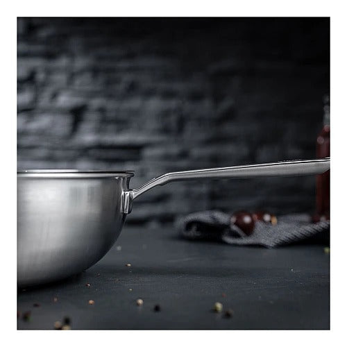 Lage close-up van de rand en de hulpgreep van de Culinary 5-Ply wok met deksel 28 cm, met het lange handvat naar rechts en een wazige achtergrond met cherrytomaten.