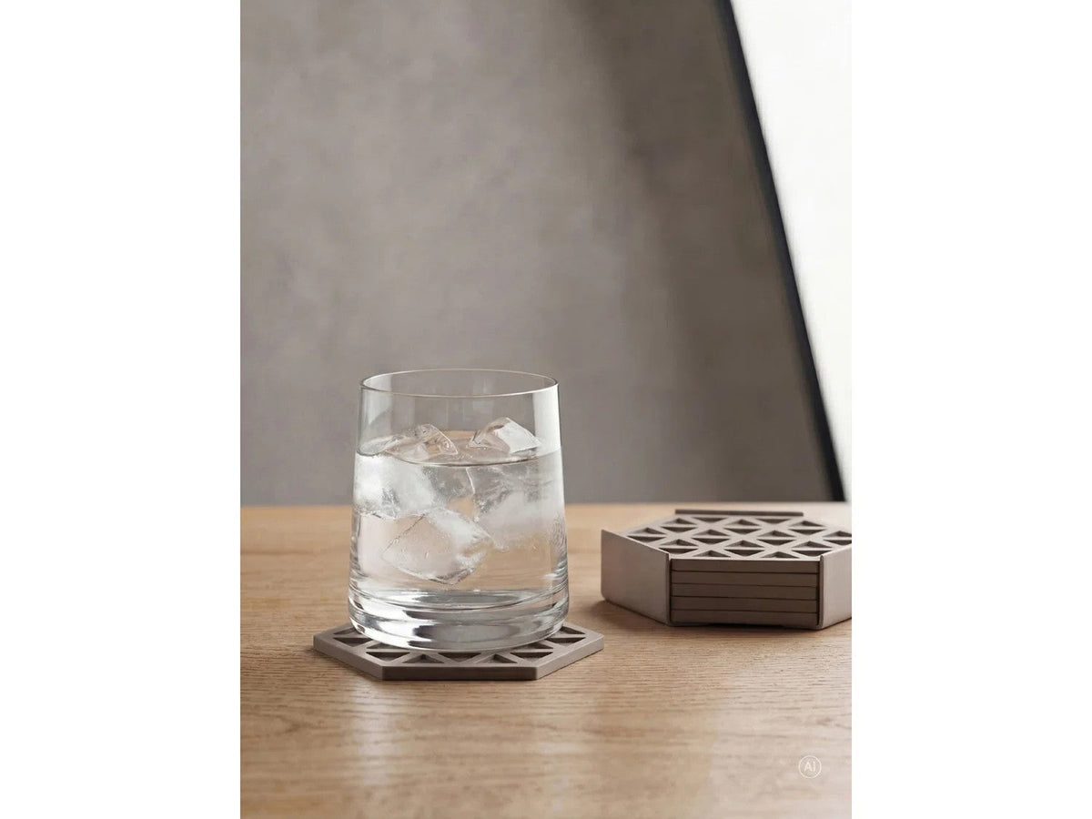 Glas water met ijsblokken op een houten tafel, staand op een taupe zeskantige onderzetter met driehoekpatroon