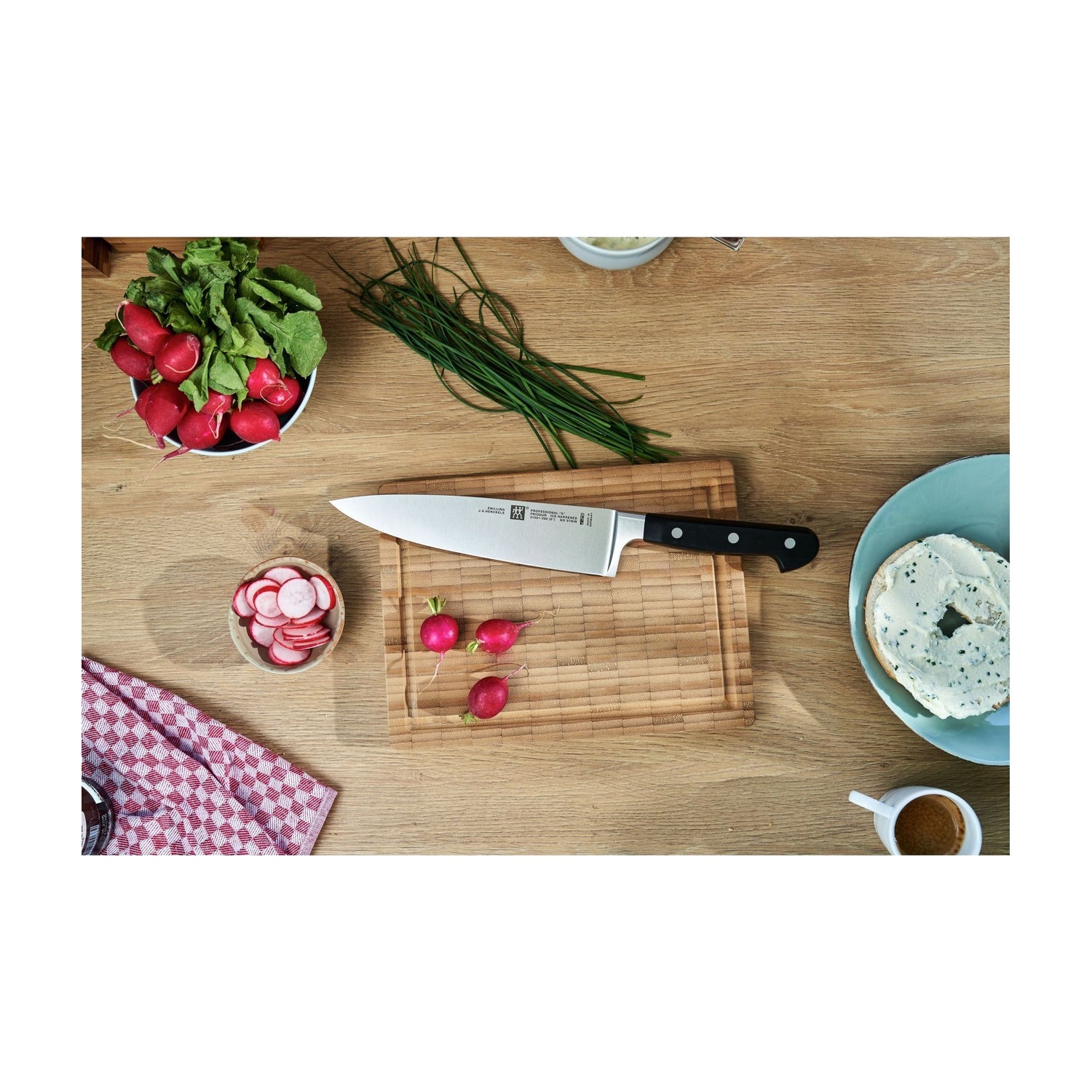 De 3 messen van de Zwilling Professional S Messenset op een houten snijplank met radijsjes en kruiden