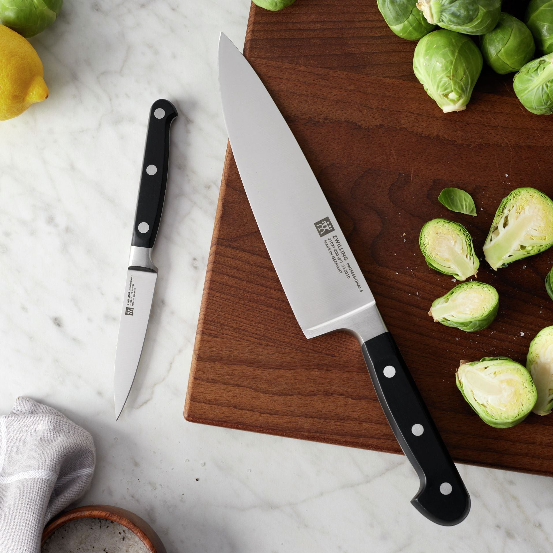 Zwilling Professional S messen uit de set op een snijplank met spruitjes