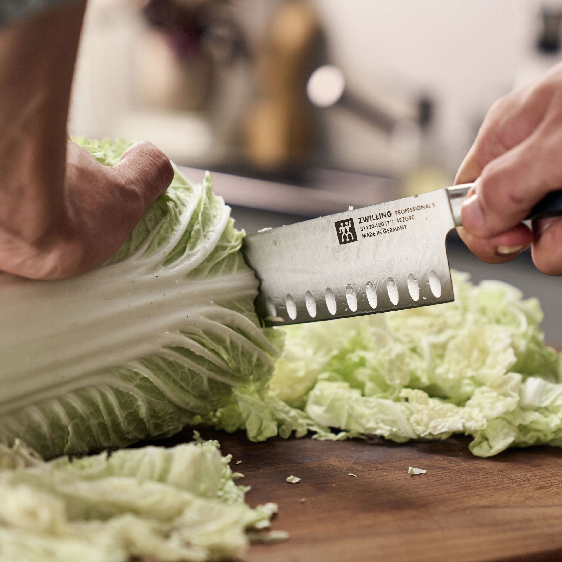 Hand snijdt met het Zwilling Professional S Santokumes door een krop witte kool