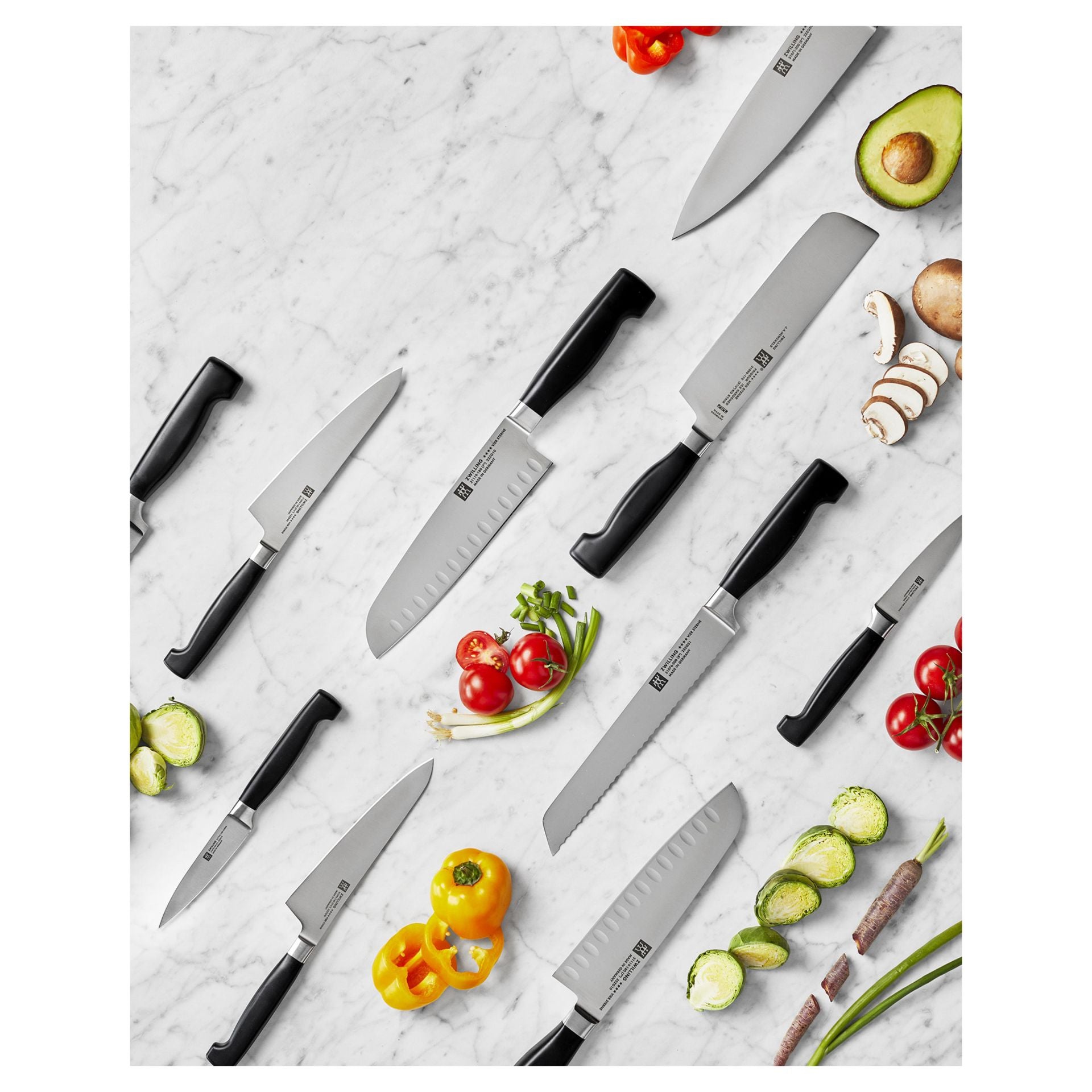 Assortiment Zwilling Four Star messen naast groenten en fruit, van bovenaf