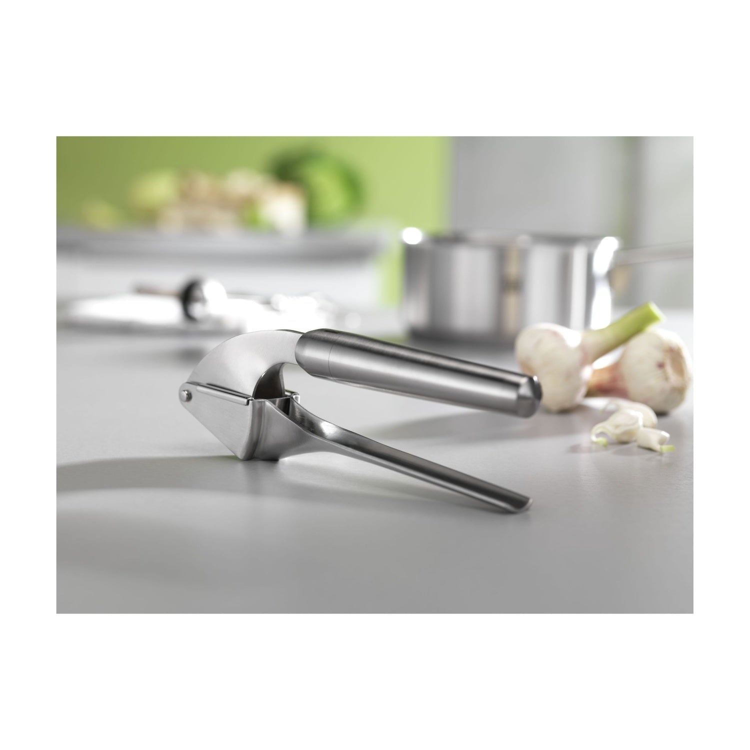 Zwilling Pro Knoflookpers naast een pan en verse knoflookteentjes