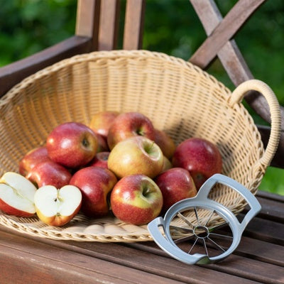 Westmark Divisorex Appel- en Perensnijder, zilver, snijring naast een rieten mand met appels