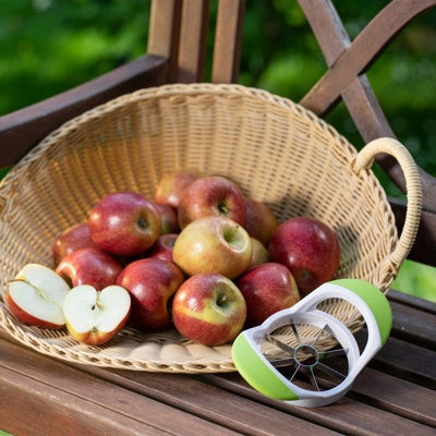Westmark Appelsnijder, wit, op een houten tuinbank naast een rieten mand met appels
