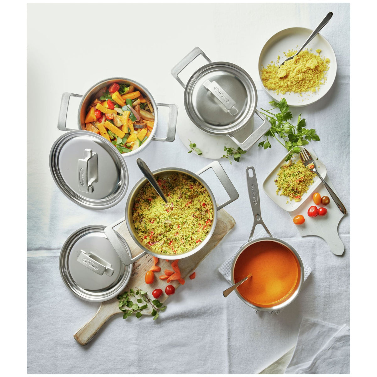 Bovenaanzicht van de Demeyere Industry 5 Pannenset gevuld met pasta, tomatensoep en couscous