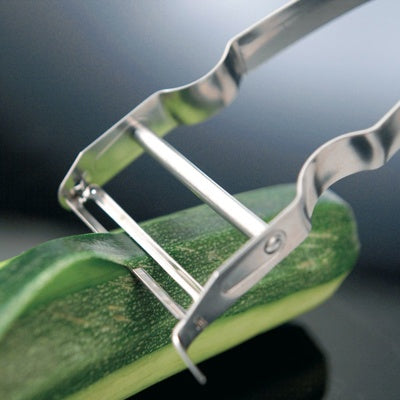Westmark Dunschiller, zilver, close-up van het dubbelzijdige mes tijdens het schillen van een courgette