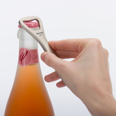 Westmark Linea Flesopener, zandkleurig, vastgehouden in een hand om een flesje bruisdrank te openen