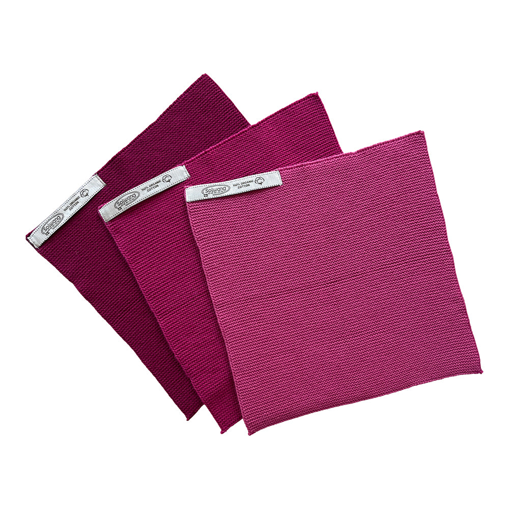 Solwang Design Vaatdoekjes set van 3 - Framboos Combi drie gebreide doekjes gewaaierd over elkaar, van donker bordeaux achteraan via framboosrood naar een lichter roze vooraan, met het Solwang-label zichtbaar op elk doekje.