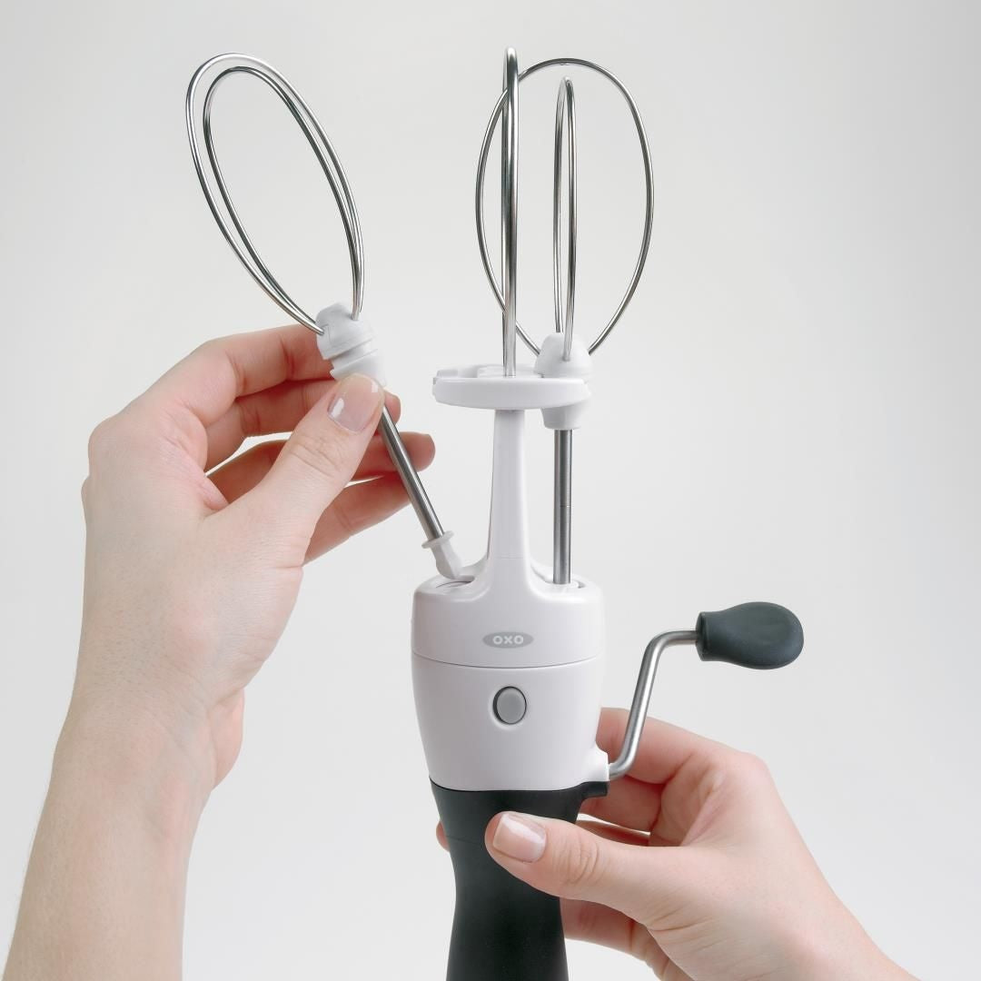 OXO Good Grips Handmixer, metalen klopper met beide handen in houder geklikt