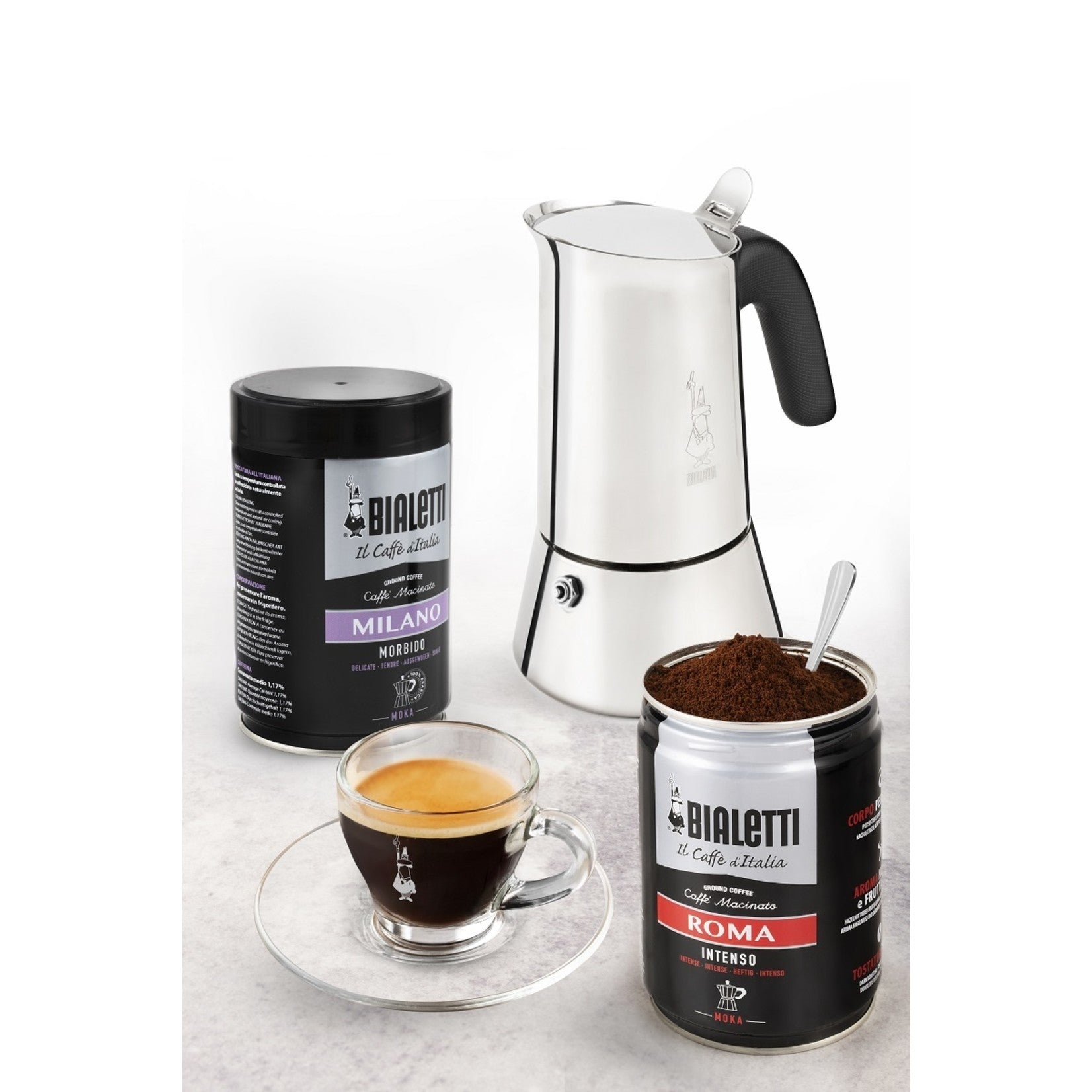 Roestvrijstalen Bialetti Venus percolator met espressokopje en twee blikken Bialetti koffie op een aanrecht.