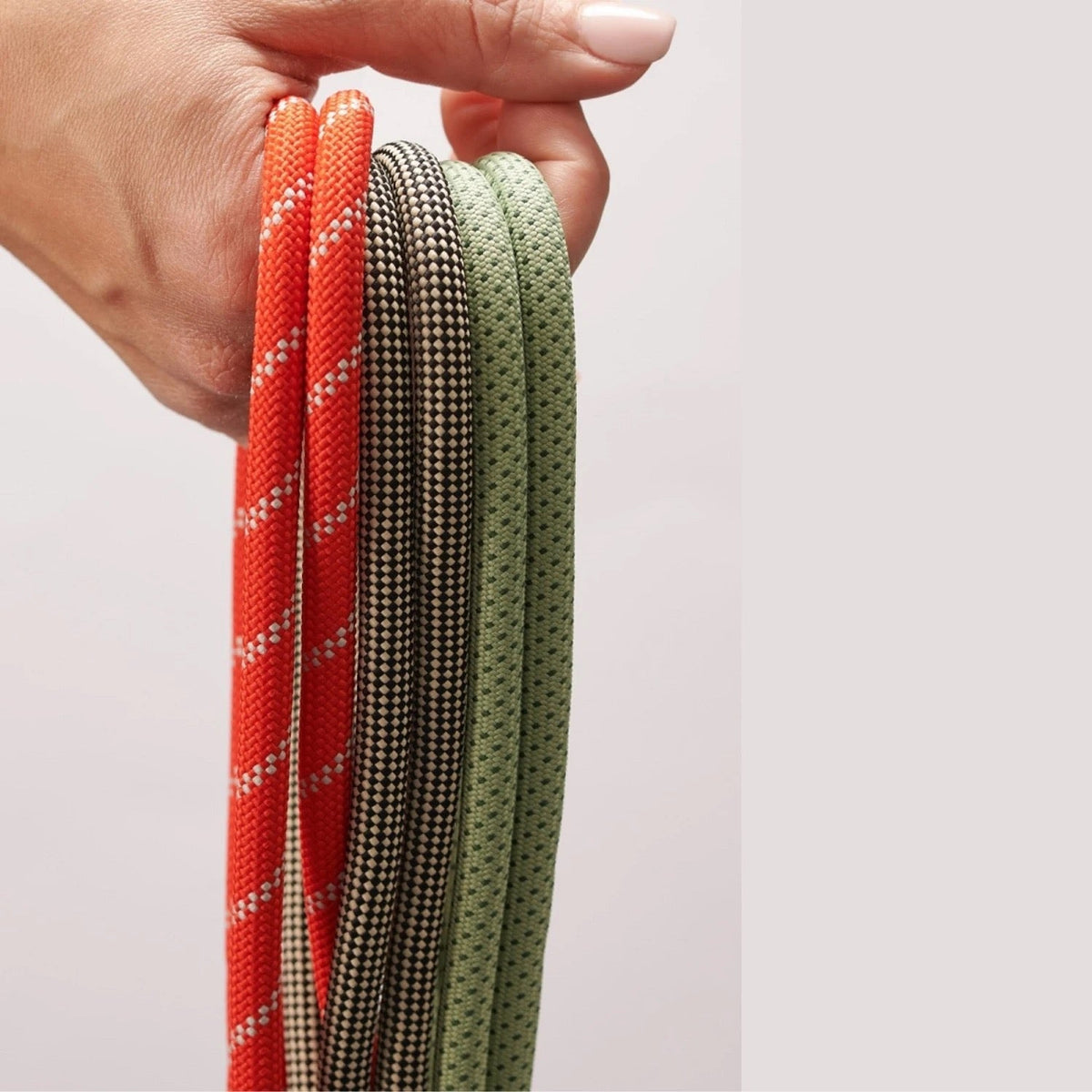 Hand houdt de Dopper Cord in Silver Red, Sandy Black en Sage Green vast